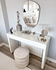 a white dressing table with a mirror and stool