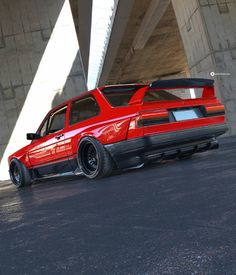 a red car is parked under a bridge