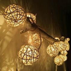 some lights that are hanging from the ceiling in front of a tree branch with several balls on it