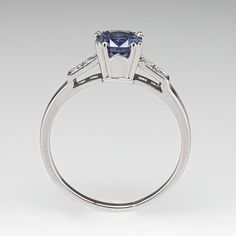 an engagement ring with a blue sapphire and two white diamonds on the side, set in 18k white gold