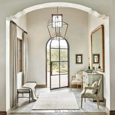 an arched doorway leads to a sitting area with chairs and a rug on the floor