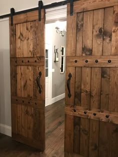 two wooden doors with black handles are open in a room that has hardwood floors and white walls