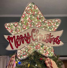 a merry christmas sign hanging from the side of a christmas tree with lights on it