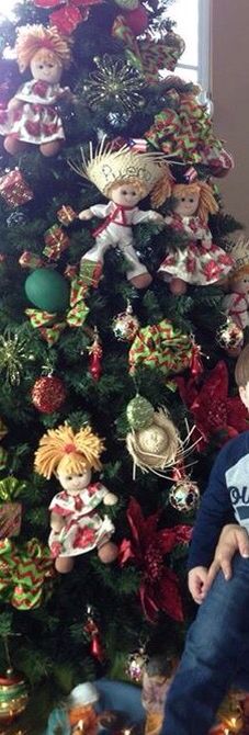 a young boy sitting in front of a christmas tree with ornaments on the top and bottom