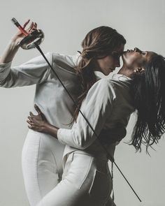 two women in white outfits are kissing each other with microphones attached to their mouths