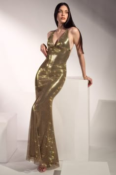 This is your moment, and this is the dress for it. The long gold formal gown empowers you with a shimmering crystal mesh fabric tailored in a classic style to reveal the beauty of your figure. An open back adorned with strings is the final touch of this luminous beauty. Cher Gowns, Gold Sparkle Prom Dress, Gold Dress Long Classy, Long Gold Dress, Gold Halter Dress, Gold Formal Gown, Nye 2025, Hollywood Glam Dress, Golden Dresses