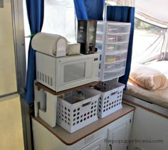 microwaves stacked on top of each other in front of a window with blue curtains