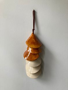 a ceramic ornament hanging on a wall with three stacked rocks in the shape of a christmas tree