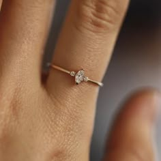 a woman's hand with a diamond ring on top of her finger, showing the side view