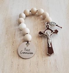 a bracelet with a cross and a first companion tag attached to it on a wooden surface