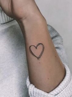 a woman's wrist with a small heart tattoo on the left side of her arm