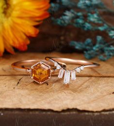 two rings on top of a piece of wood with flowers in the background