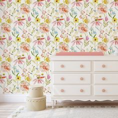 a white dresser sitting in front of a wallpapered wall with flowers on it