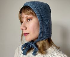 a woman wearing a blue knitted hat with a bow