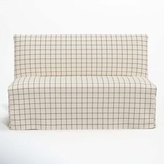 a white and black checkered couch sitting on top of a white floor next to a wall