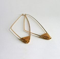 Long Gold Beaded Triangle Hoop Earrings ~ Dramatic and a little edgy, these gold triangle hoops make a statement. 14k gold fill wire is hand shaped and hammered into long graceful triangle hoops and tipped with tiny gold seed beads. The length of these earrings gives them alot of movement and beaded tips seem to float along the jawline. Lightweight and very wearable, perfect if you like bigger earrings but can't wear anything heavy. 3 1/8" top to bottom and about 1 1/8" at the widest point. They hang below the chin. Your purchase will arrive beautifully packaged in a floral jewelry box tied with a ribbon bow ready for giving, or even better, treating yourself. They are also available in Sterling Silver ~ https://www.etsy.com/listing/166344884/long-modern-beaded-triangle-hoop-silver? I also Gold Triangle Minimalist Earrings, Minimalist Gold Triangle Earrings, Gold Triangle Metal Jewelry, Triangle Gold Metal Earrings, Gold Triangle Metal Earrings, Nickel-free Gold Triangle Jewelry, Modern Triangle Gold Hoop Earrings, Everyday Gold Triangle Earrings, Bohemian Gold Triangle Jewelry