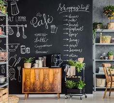 a chalkboard wall in the corner of a room with furniture and plants on it