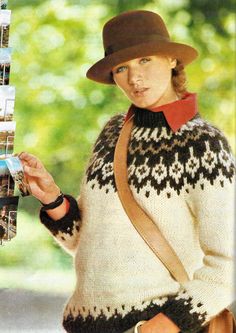 a woman in a hat and sweater holding a cell phone