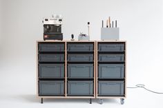 a shelf with many drawers on top of it next to a coffee maker and pencils