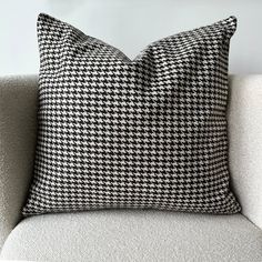 a black and white pillow sitting on top of a gray couch next to a wall