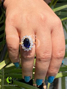 a woman's hand with blue and white nail polish holding an oval shaped ring