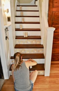 a woman sitting on the floor in front of stairs