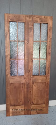 two wooden doors with frosted glass in front of a gray wall and white tile floor