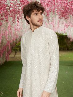 a man standing in front of pink flowers