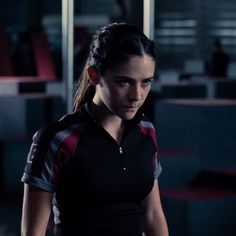 a woman in black and red shirt standing next to a wall with a quote on it