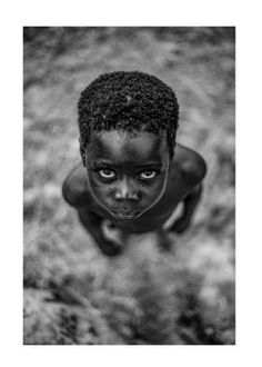 a black and white photo of a young boy looking up at the camera with his eyes wide open