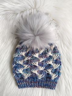 a blue and white knitted hat with a pom - pom on top