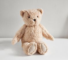 a teddy bear sitting on a white surface with a gray wall in the back ground