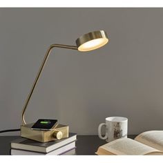 a lamp that is on top of a table next to some books and a cup