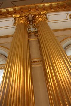 two gold pillars in the center of a room with columns on either side and ceiling