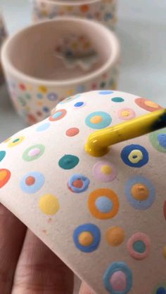 a person is holding an umbrella shaped like a polka dot paper cup with a yellow handle