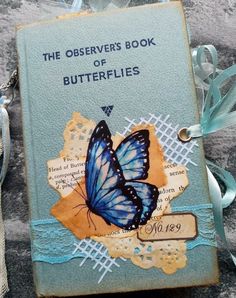 an old book with a blue butterfly on it and ribbon attached to the front cover