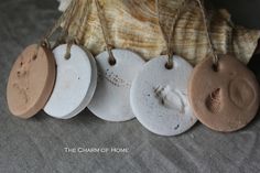 four ceramic tags hanging from strings on a piece of sea shell with seashell in the background