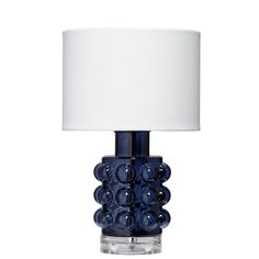 a blue glass table lamp with a white shade on the top and bottom part of it