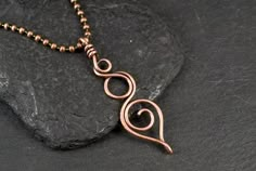 a copper necklace on a black rock