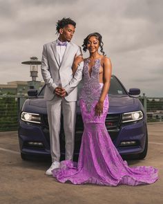 a man and woman in formal wear standing next to a purple car on the tarmac