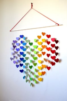 a rainbow heart mobile hanging on a wall with strings attached to it's sides