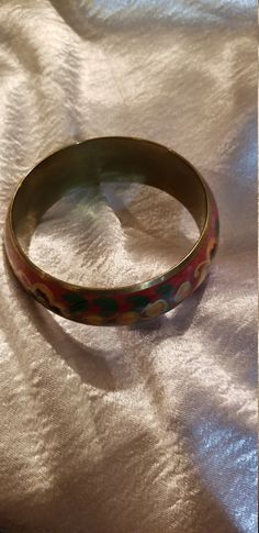 Thick Red floral enamel bracelet Enamel over brass with a red background and yellow and orange flowers with hints of gold and green leaves. Some tarnish on inside but otherwise in very good condition 2 1/2 In. inner diam best for a smaller wrist Just a teensy bit under one inch thick Red Metal Cuff Bracelet Bangle, Red Metal Bangle Cuff Bracelet, Vintage Handmade Red Bangle, Vintage Red Round Bangle, Red Round Metal Bangle, Red Bracelets For Festivals, Red Bohemian Metal Bangle, Red Metal Bohemian Bangle, Bohemian Red Metal Bangle