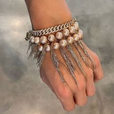 a woman's hand wearing a bracelet with pearls and chains on the wrist,