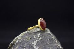 Anatolian Handcrafted Agate Stone Ring made 24K Gold Plated 925 sterling silver and used Natural Agate Gemstone.Handcrafted hammered full round ring band size measures 2mm in width and Agate Gemstone 15x11mm.--Agate Gemstone Means--Also called Red Eye Agate, the meaning of red kind of agate is opening up. It is a gemstone that helps you open your heart and welcome new energies into it. When you use or touch a red eye agate, your heart opens and mind welcomes new ideas without hesitance.Metal : 9 Yellow Gold Chalcedony Ring Gift, Yellow Gold Rings With Natural Stones For Gift, Gold Agate Cabochon Rings, Gold Agate Rings For Anniversary, Gold Agate Rings With Polished Finish, Unique Gold Agate Ring, Handmade Gold Chalcedony Rings, Handmade Agate Rings As Gift, Handmade Agate Rings For Gift