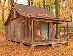 an outhouse in the woods with two chairs on the porch and one chair next to it