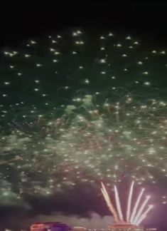 fireworks are lit up in the night sky above a large building with many lights on it