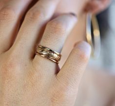 a close up of a person's hand with a gold ring on their finger