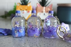 three glass bottles with key chains attached to them sitting on a counter next to other items