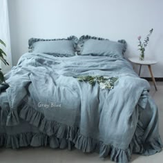 an unmade bed with blue linens and ruffled bedspread