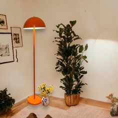 an orange floor lamp sitting next to a potted plant